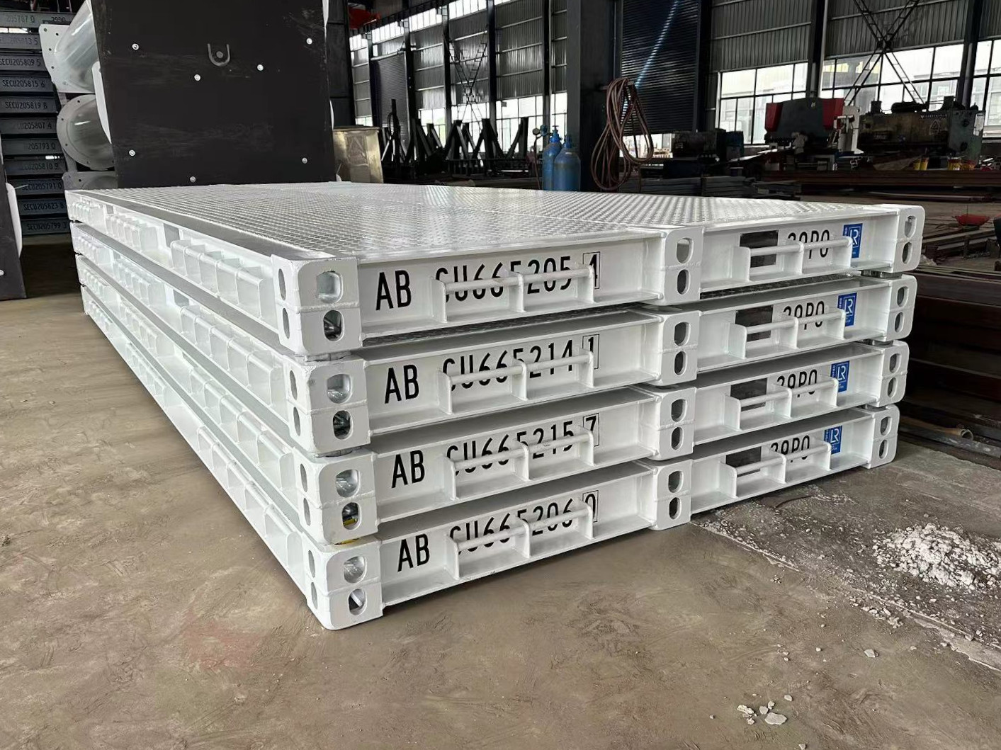 A stack of 4 white platform containers sitting in a warehouse.