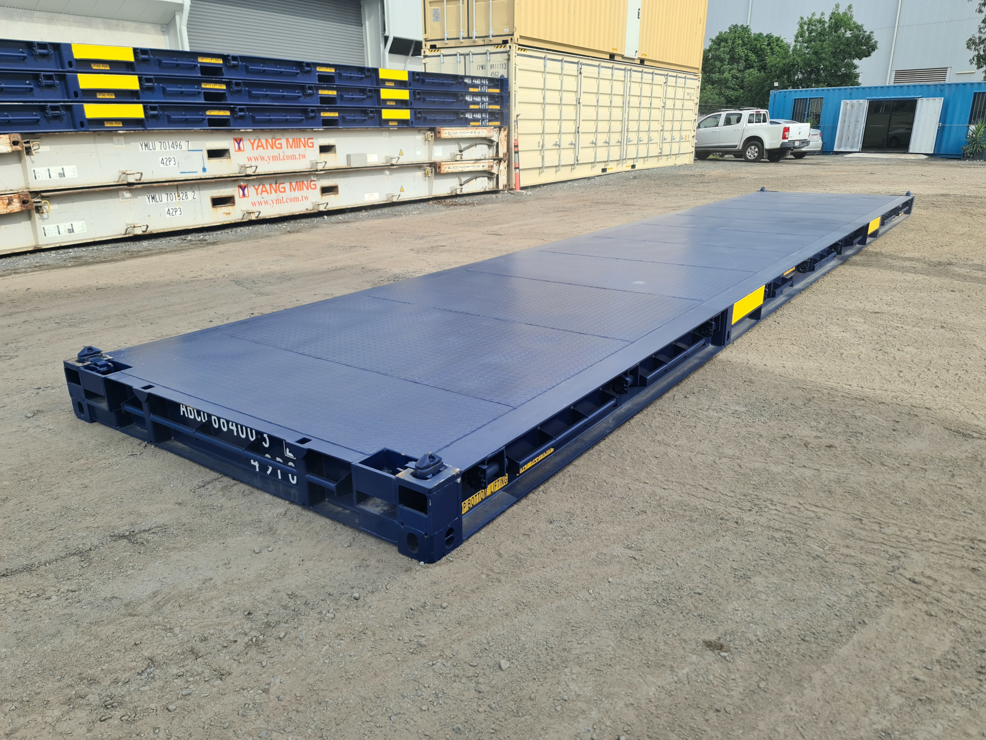 A deep blue 40ft long bolster/platform container on the ground.